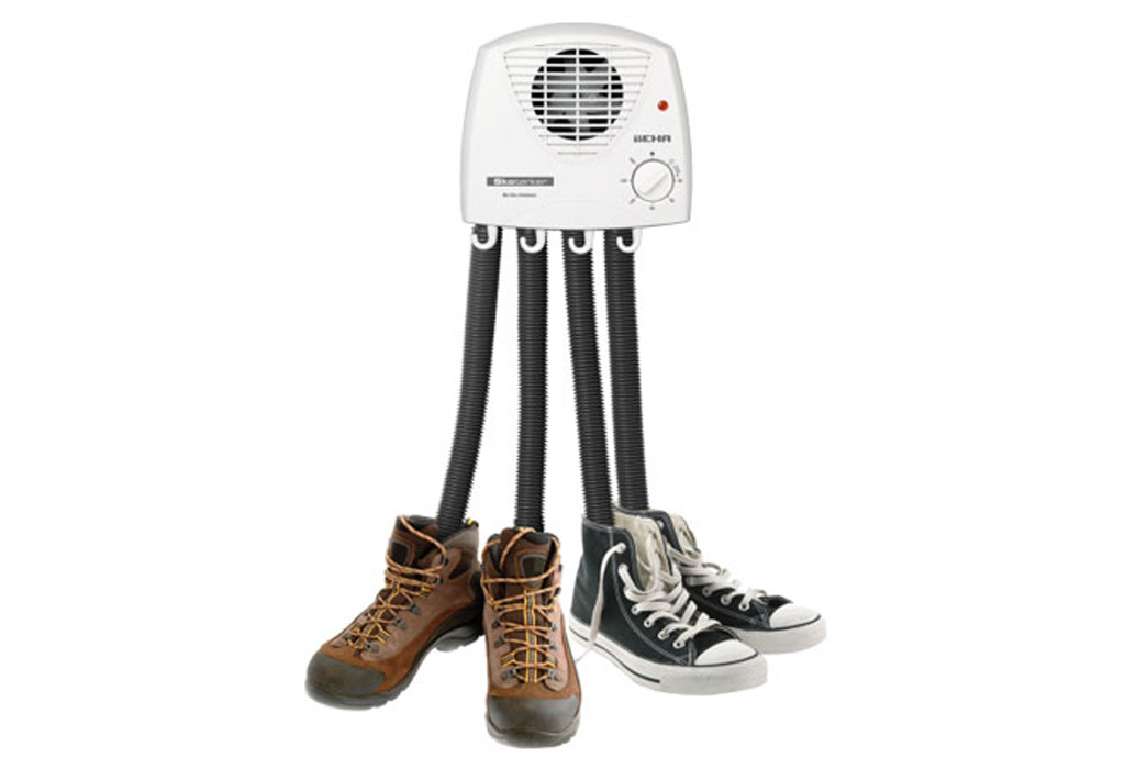 a shoe dryer with four flexible tubes is inserted into two pairs of boots and sneakers, drying them.